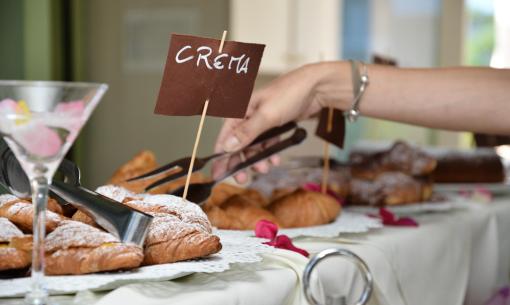 Mano prende croissant alla crema, atmosfera dolce e invitante.