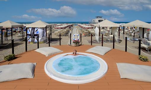 Spiaggia con jacuzzi, lettini e ombrelloni, vista mare.