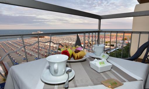 Colazione con vista mare e spiaggia, tazze e dolci sul tavolo.